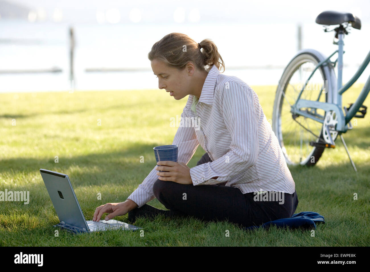 Woman working on laptop at a beach park Stock Photo