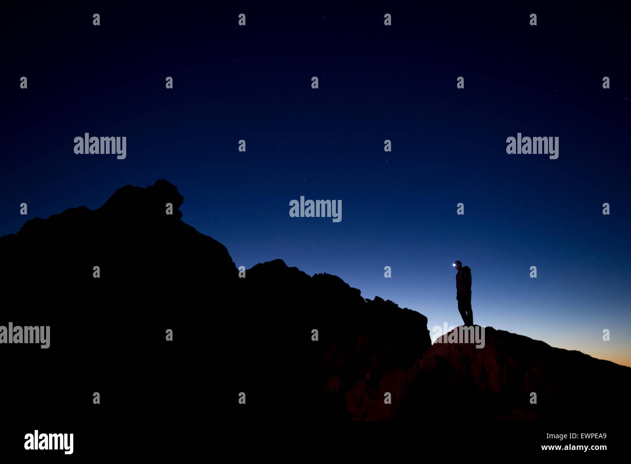 Silhouetted hiker with headlamp at twilight Stock Photo