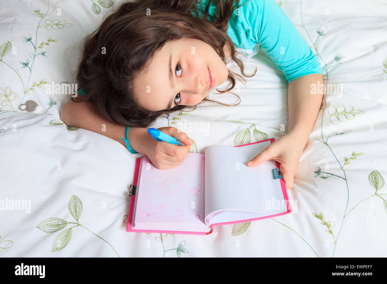 Girl writing diary in bed Stock Photo