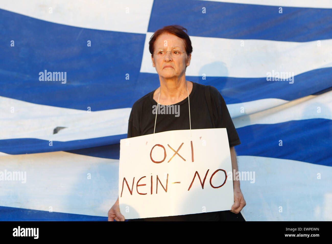 Athens, Greece. 29th June, 2015. Supporters of the NO vote in the upcoming referendum holds a banner with colors of the Greek flag reading 'NO, OXI' during a rally at Syntagma. Anxious Greek pensioners swarmed closed bank branches and long lines snaked outside ATMs as Greeks endured the first day of serious controls on their daily economic lives ahead of a July 5 referendum that could determine whether the country has to ditch the euro currency and return to the drachma. © Aristidis Vafeiadakis/ZUMA Wire/Alamy Live News Stock Photo