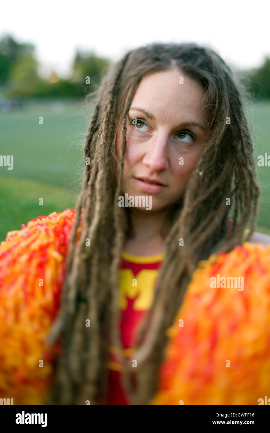 Cheerleader with dreadlocks and pom poms with look of desperation Stock Photo