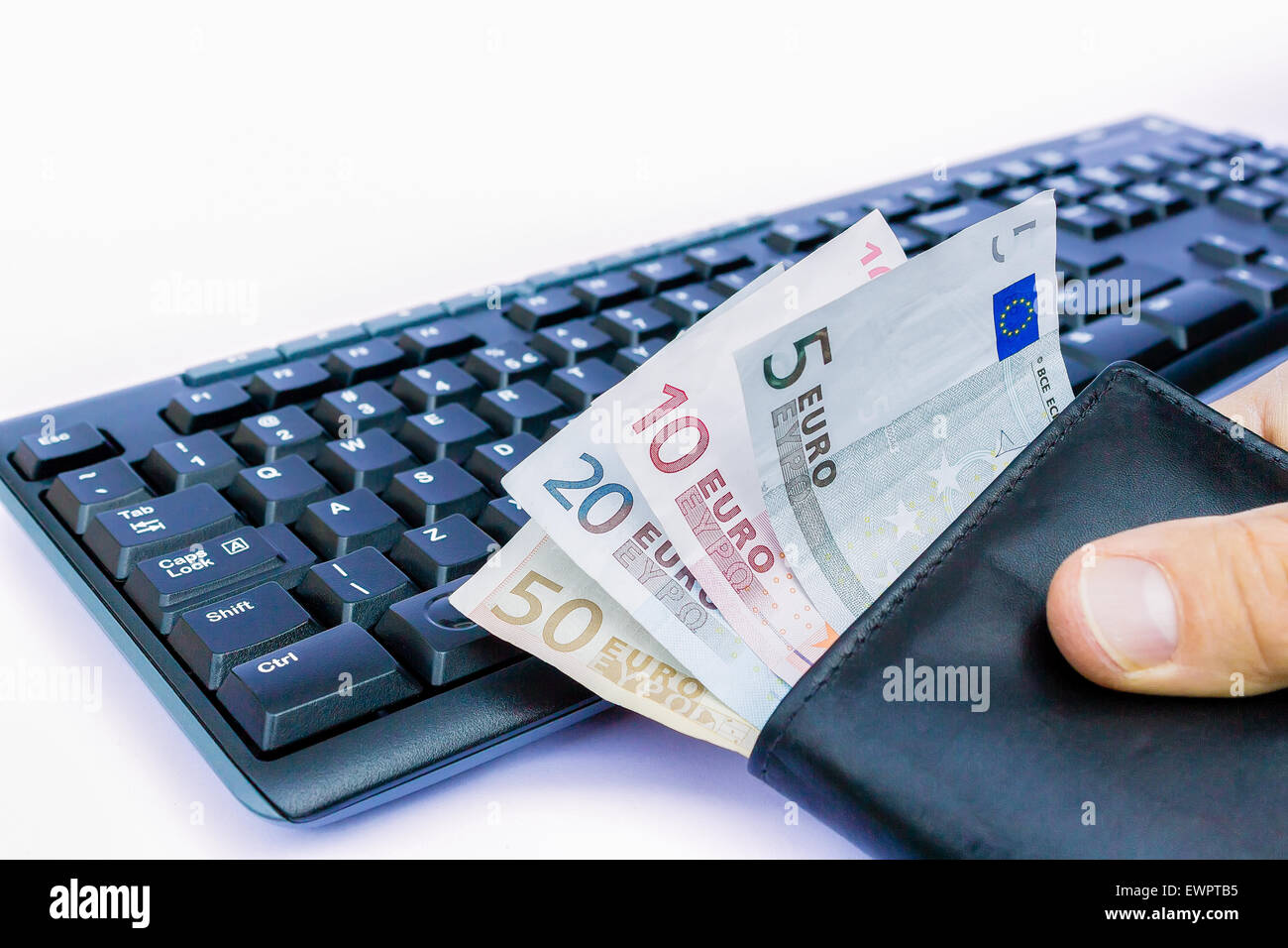 Hand holding wallet with euro money at keyboard isolated on white background Stock Photo