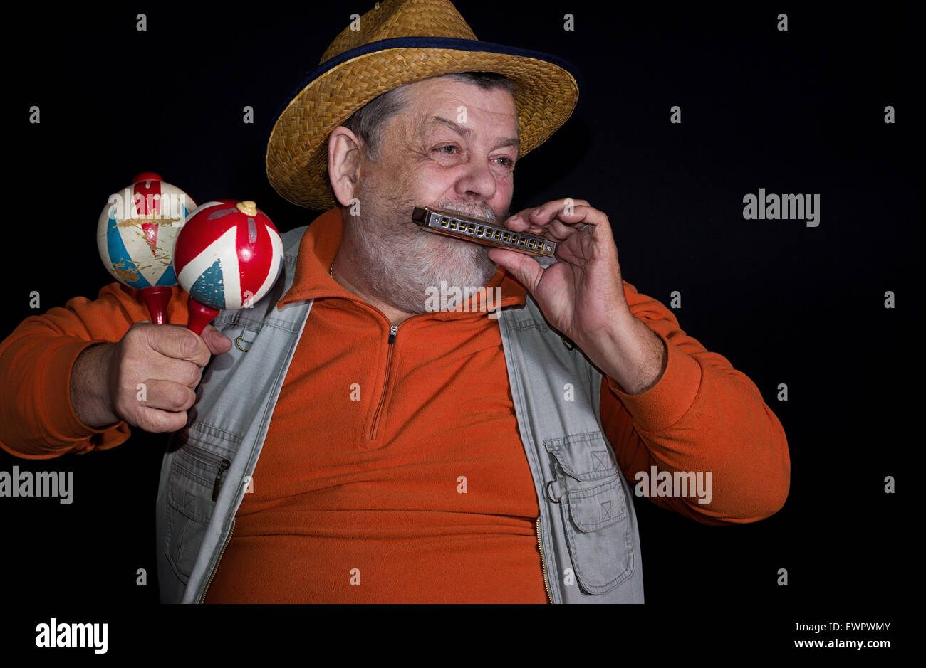 Senior musician with mouth-organ and maraca playing on a stage Stock Photo
