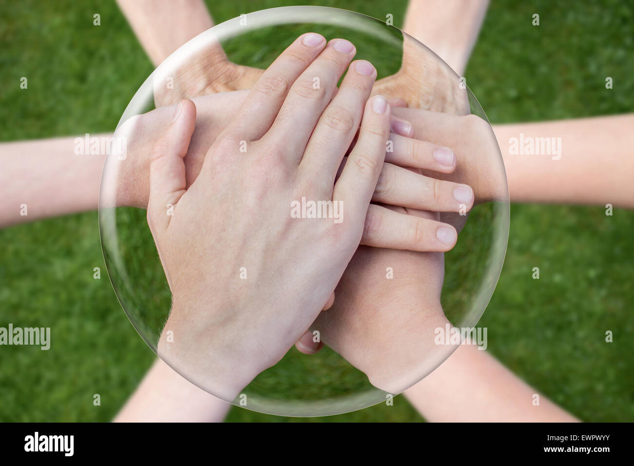 Hands arms above grass uniting joining in glass sphere Stock Photo