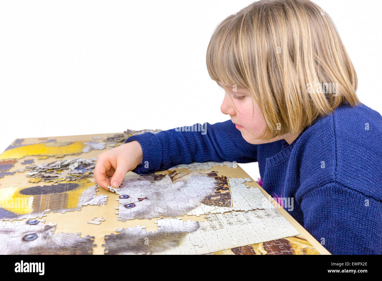 Young caucasian girl making jigsaw puzzle of cats on table isolated on