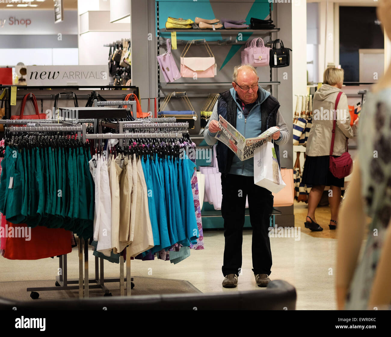 Man reading newspaper in clothes shop. Stock Photo