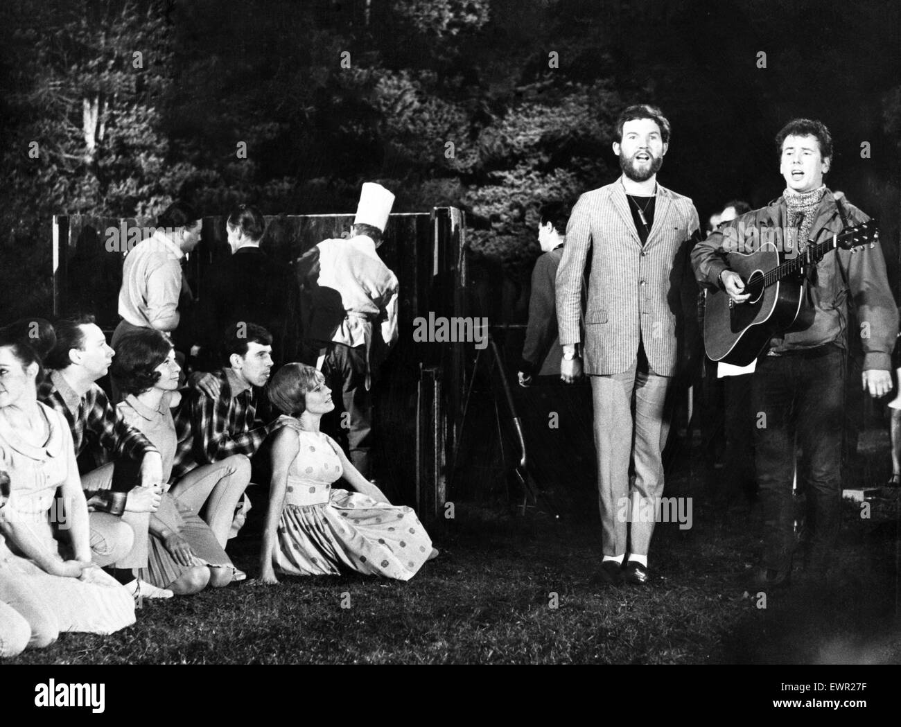 During filming of the BBC White Heather Club programme. The scene is a barbecue in the grounds of Dunblane Hydro, Perthshire. People watching folk singers Robin Hall   (left) and Jimmie Macgregor. 14th September 1966. Stock Photo