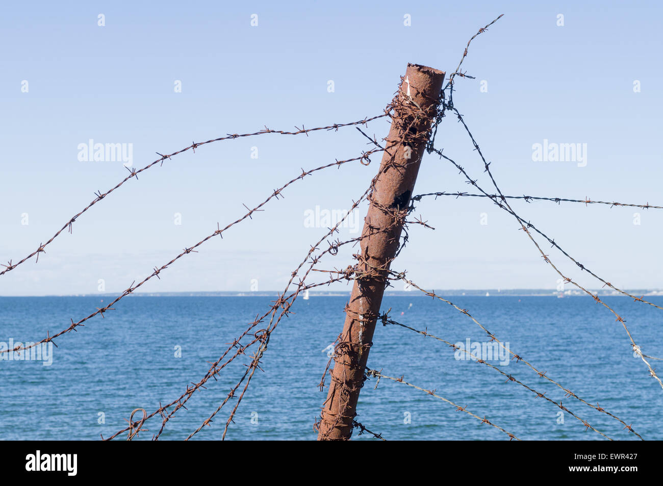 Old barbed wire fence and rusty post against sea and sky Stock Photo ...