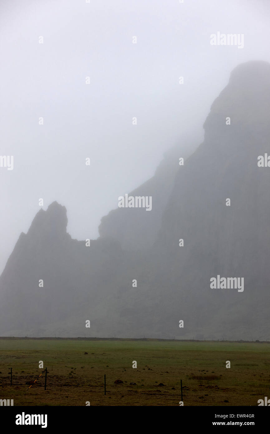 low mist and cloud limited visibility in the mountains with troll faces in the rock Iceland Stock Photo
