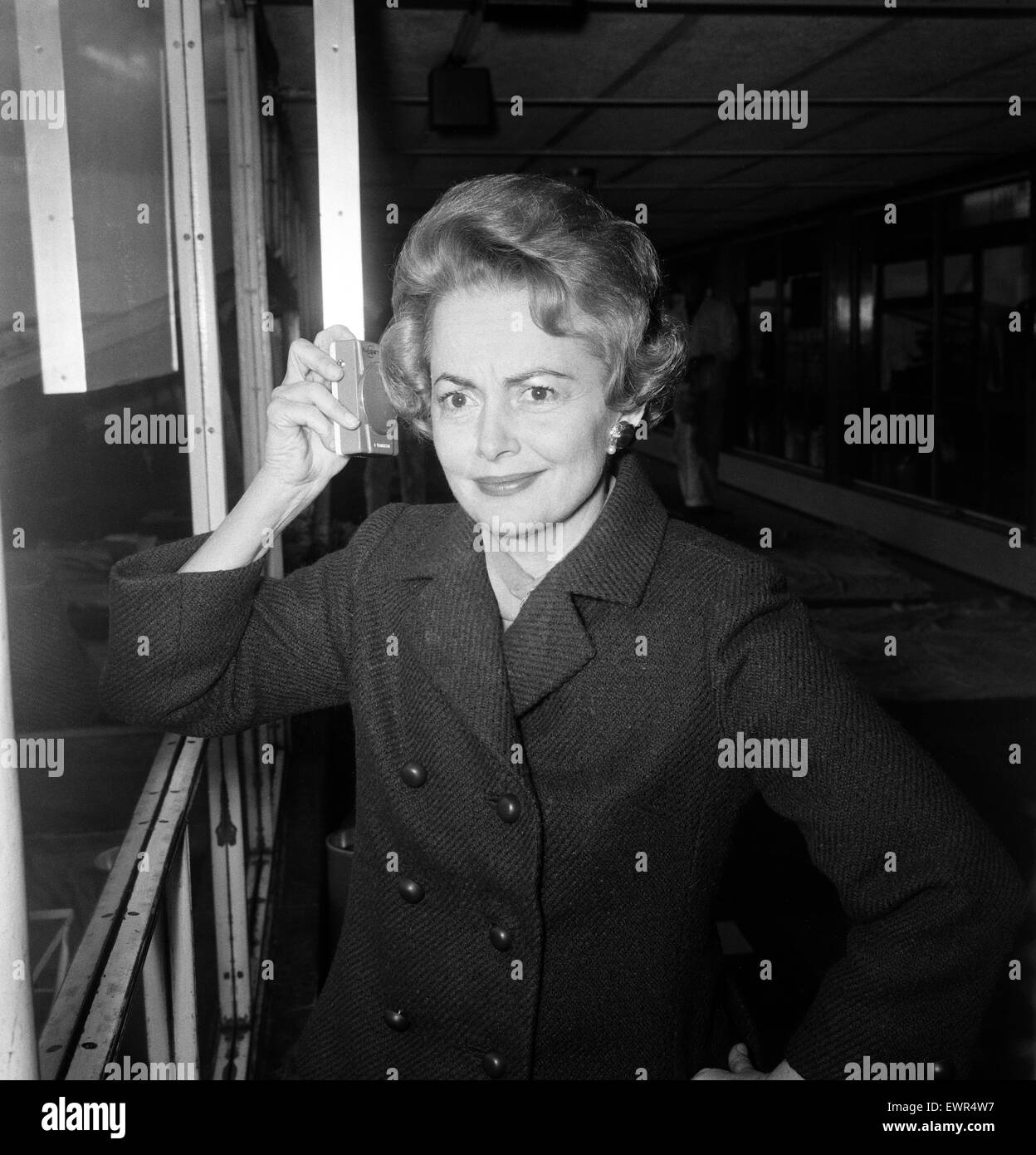 Olivia De Havilland listens to the budget at London Airport while waiting for a flight home to Paris. 15th April 1964. Stock Photo