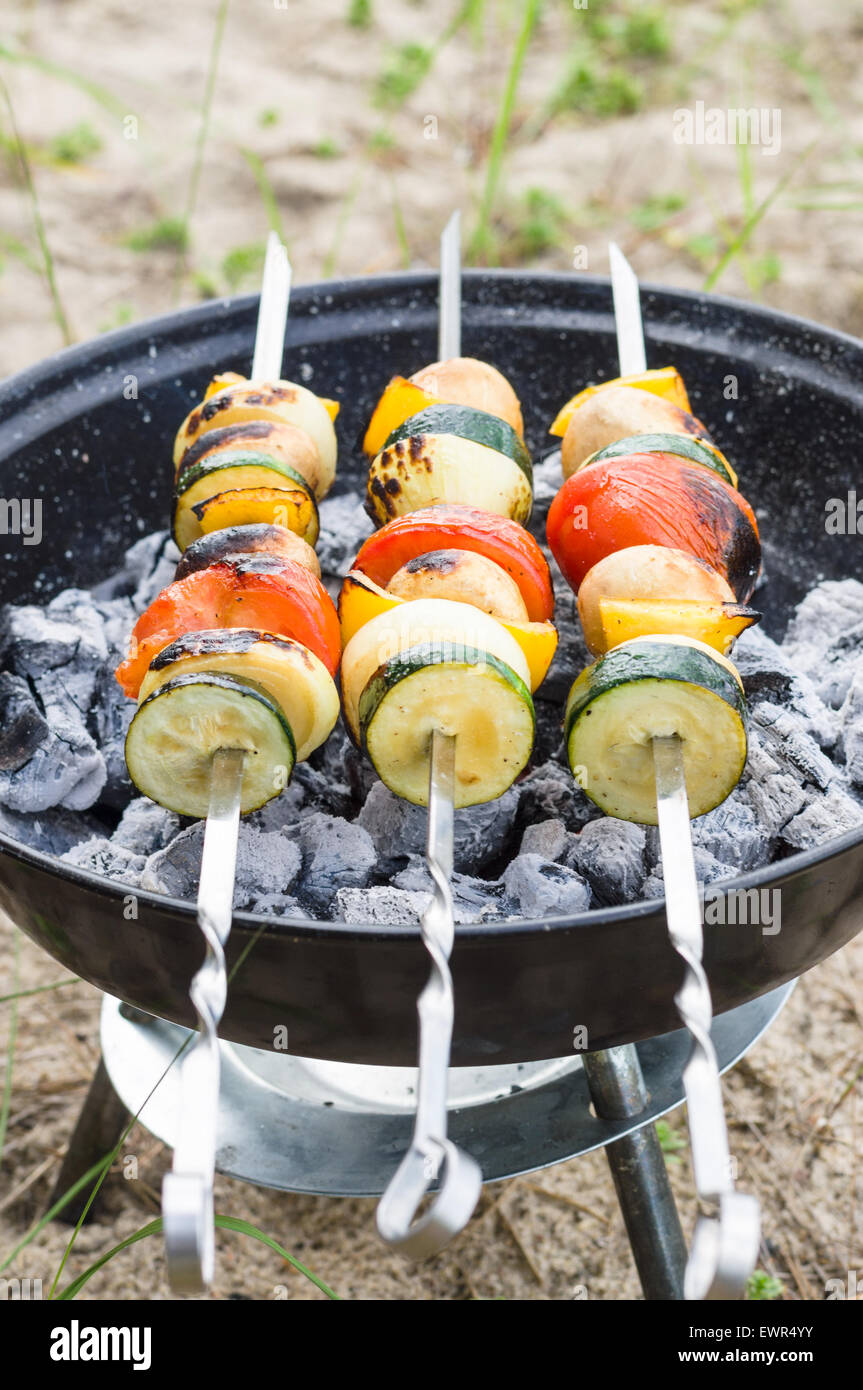 Vegan shish kebab on skewer. Fresh vegetables prepared on a grill charcoal, outdoors. Stock Photo
