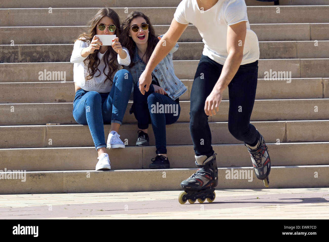Roller skating boy with friends in town Stock Photo