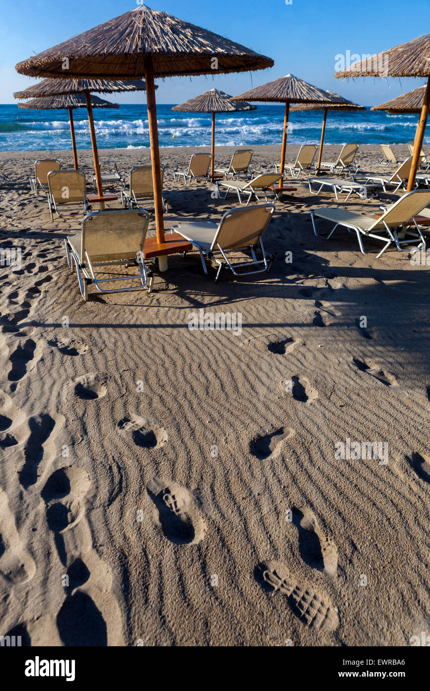 Footsteps on beach with straw umbrellas and sun loungers Rethymno Crete Greece Sand beach Europe Stock Photo