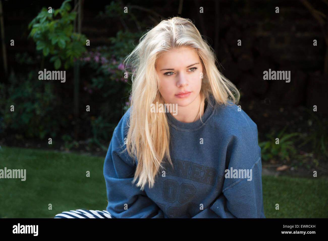A very pretty beautiful girl in a sweat shirt in the garden of her home in London Stock Photo