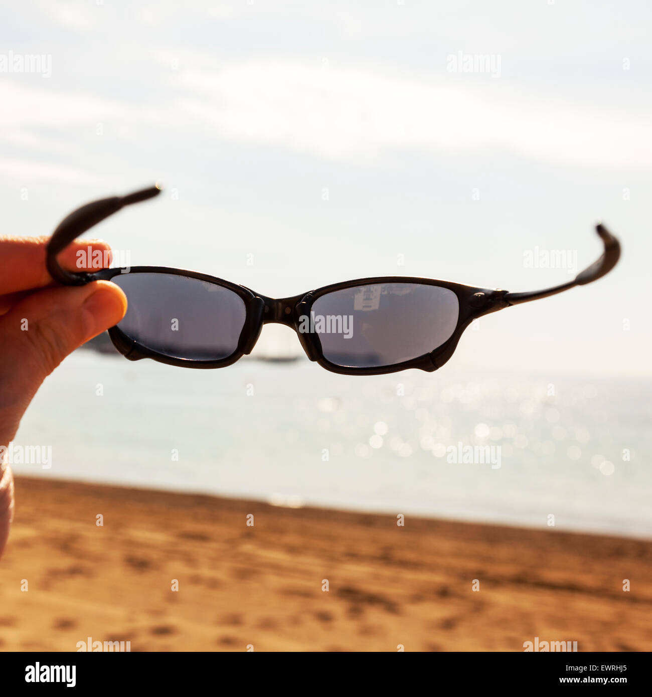 Sunglasses putting on beach holiday sun eye protection Oakley sunglass  Santa Eulalia Del Rio Ibiza Spain Spanish resort beach Stock Photo - Alamy
