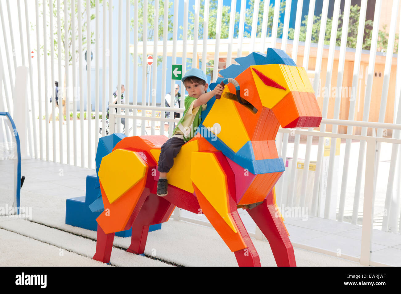 Kinder booth at EXPO 2015 in Milan. Children doing sports: wooden horse riding Stock Photo
