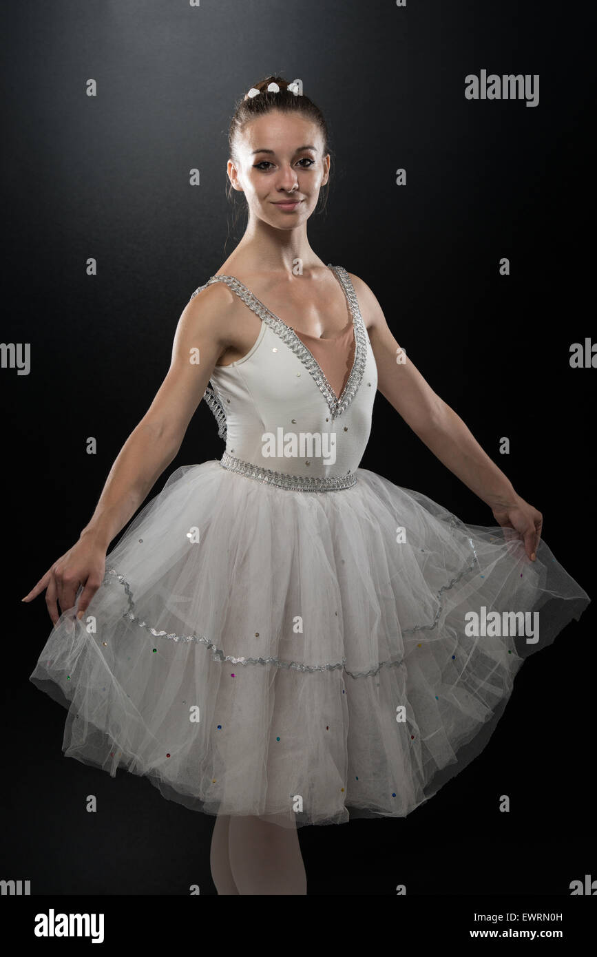 Beautiful Female Ballet Dancer On A Black Background - Ballerina Is Wearing A Tutu And Pointe Shoes Stock Photo
