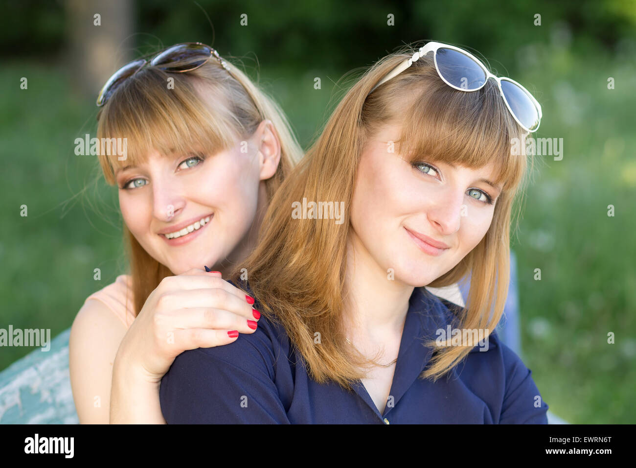 Two pretty women having fun at the summer park. Twins girls are posing looking to the camera Stock Photo