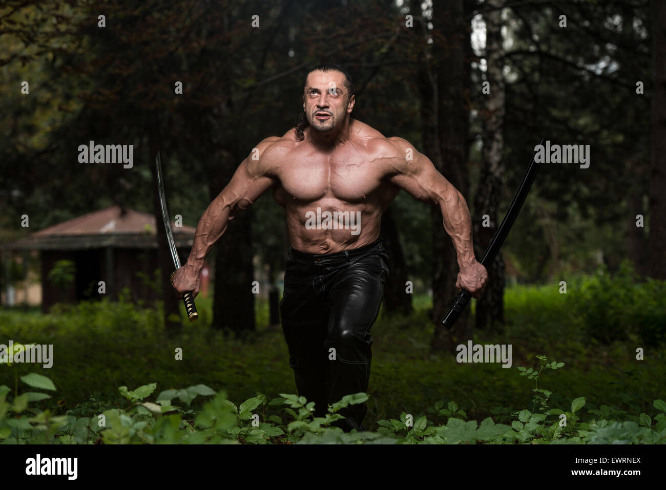 Action Hero Muscled Man Holding A Ancient Sword Standing In Forest