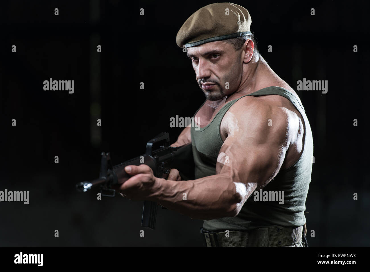 Action Hero Muscled Man Holding Machine Gun Standing In Abandoned