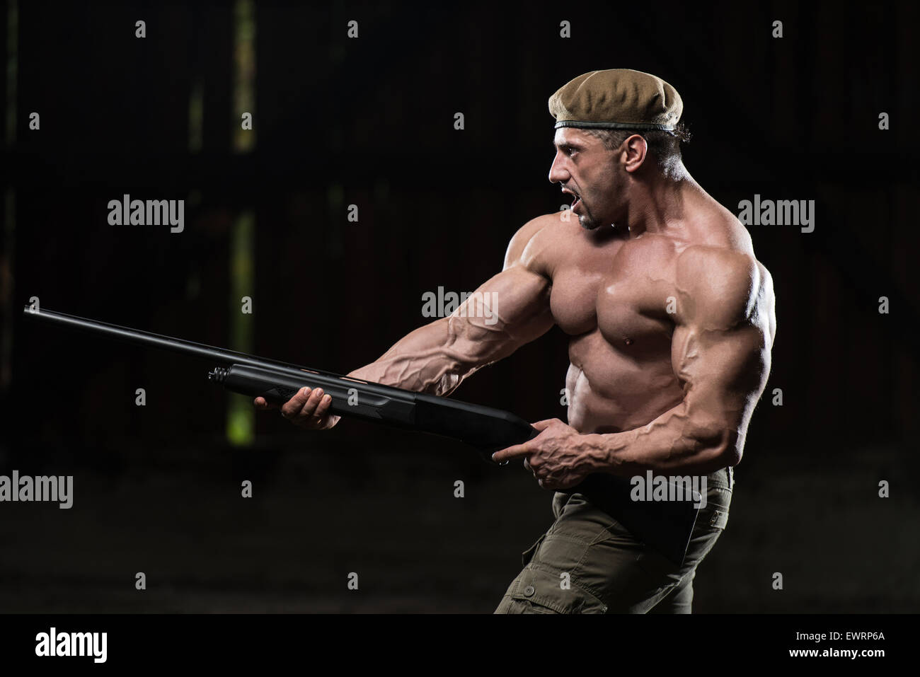 Action Hero Muscled Man Holding Machine Gun Standing In Abandoned