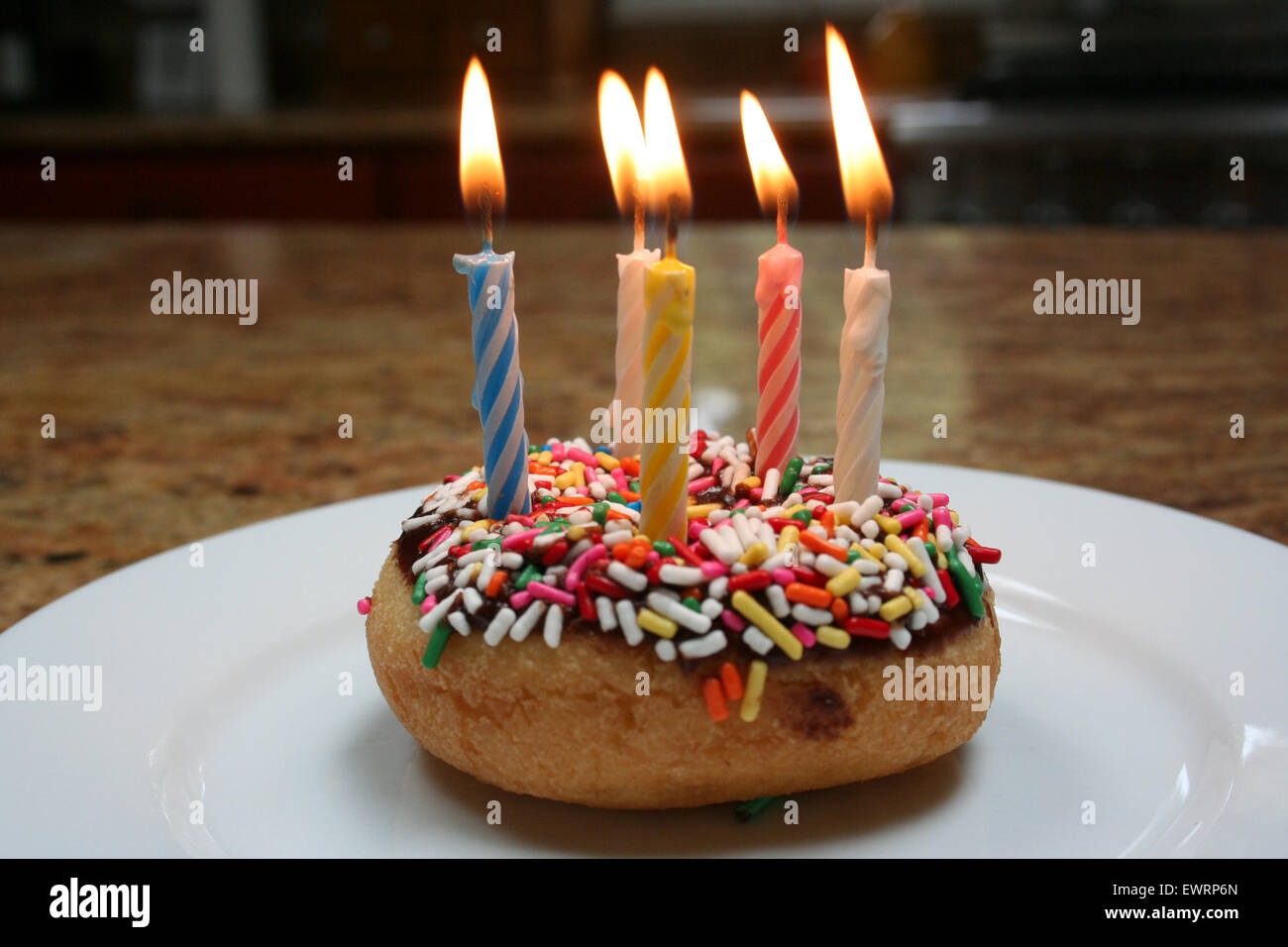 Birthday donut with sprinkles and striped candles Stock Photo Alamy