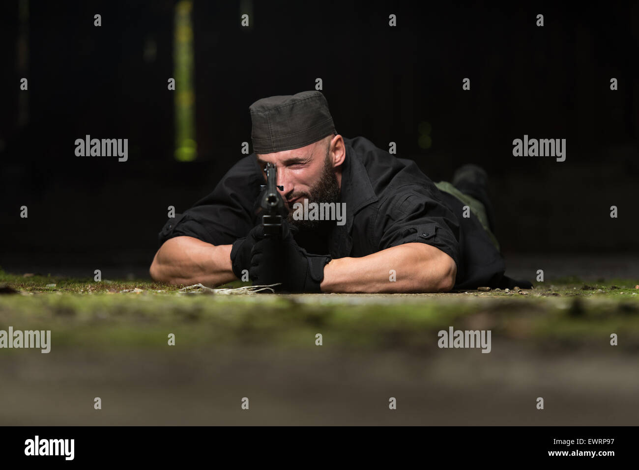 Action Hero Muscled Man Holding Machine Gun - Lying In Abandoned Building Wearing Green Pants Stock Photo