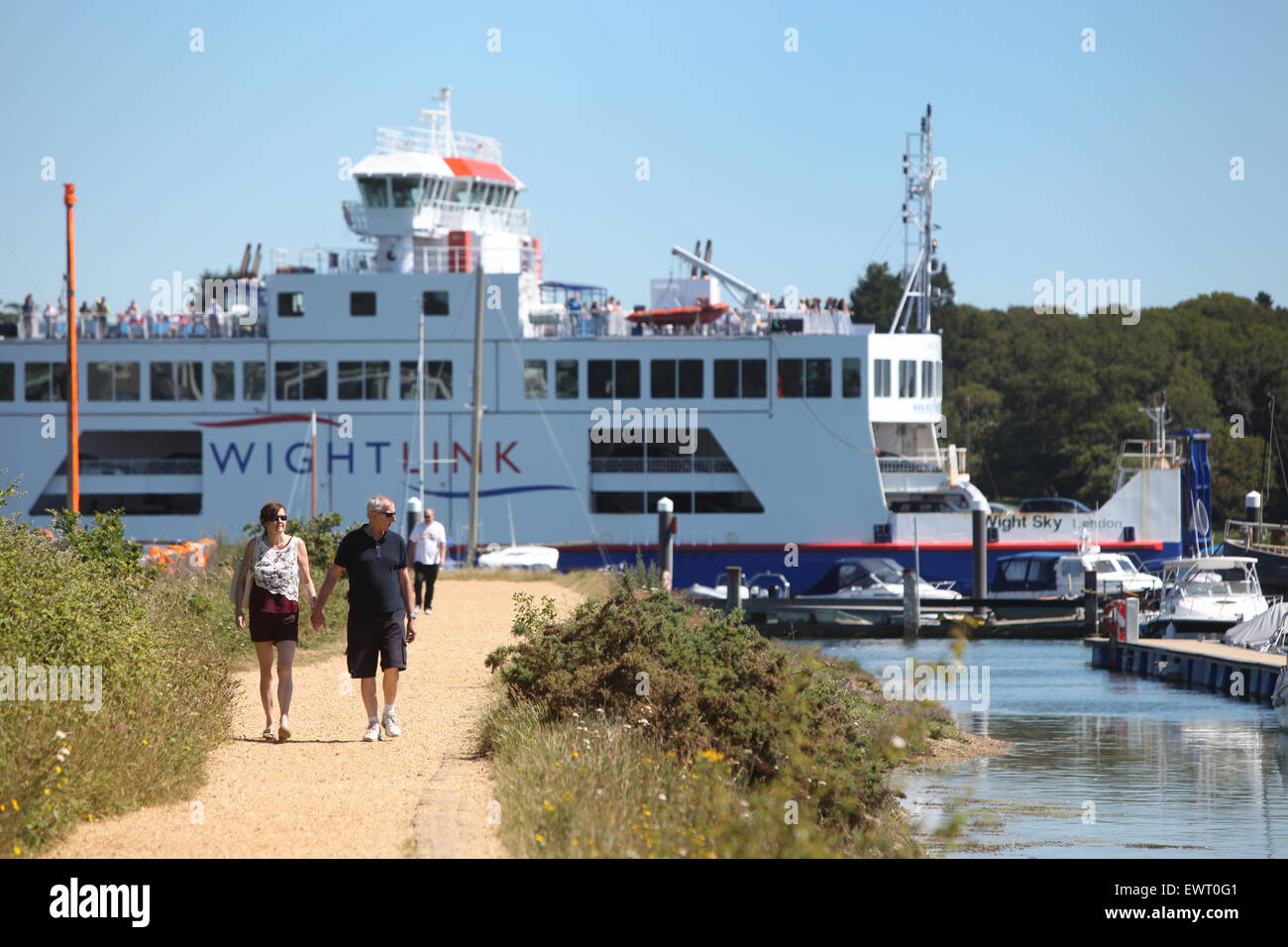 Walkers on the Solent Way between Lymington and Keyhaven with the Wight Link ferry passing in the background Stock Photo