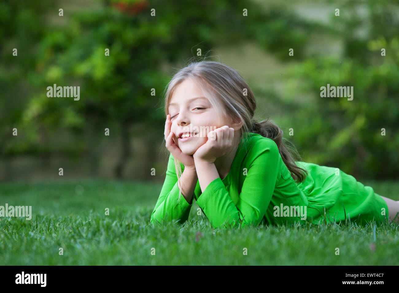 portrait of little girl laying on the grass in summer environment Stock ...
