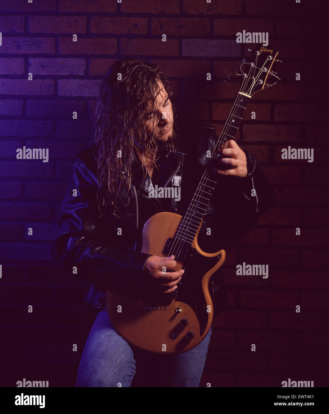 Rock guitarist with long blond hair, wearing a leather jacket, playing