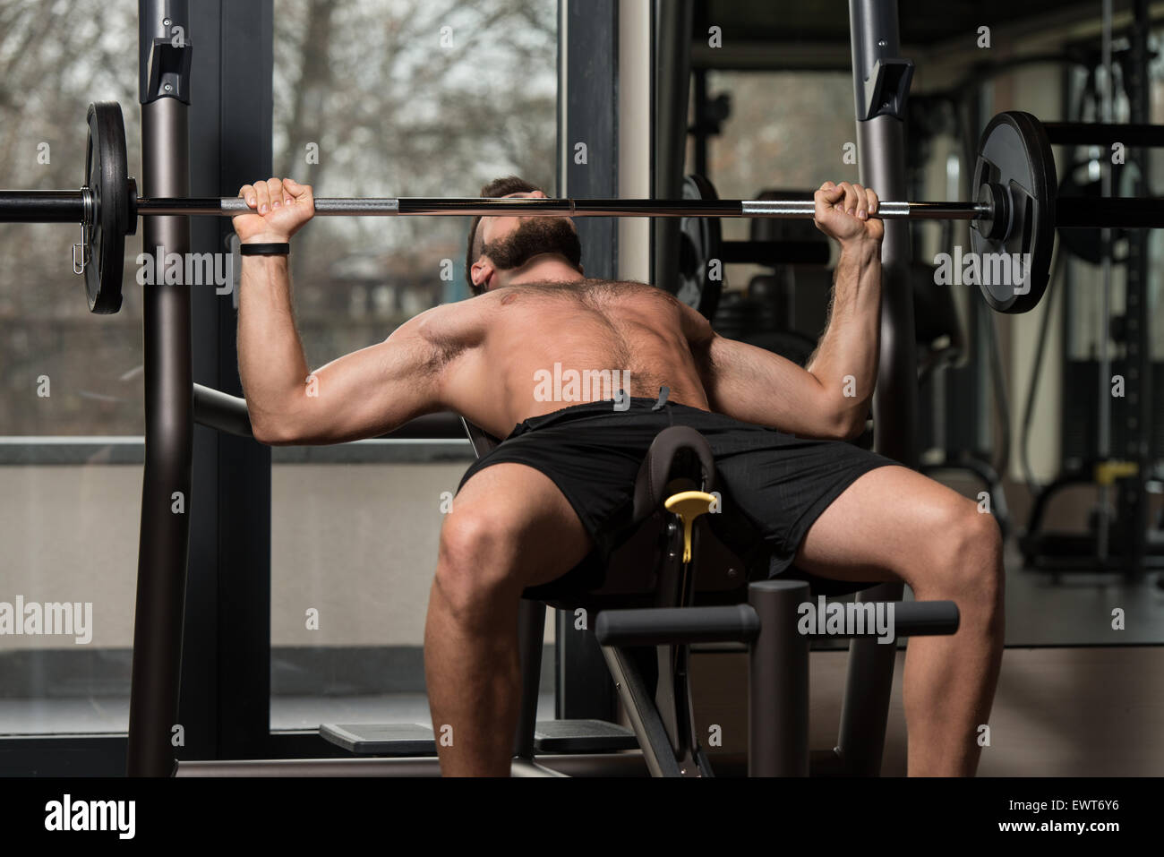 Handsome Man Is Working Out Chest With Barbell In A Modern Gym Stock