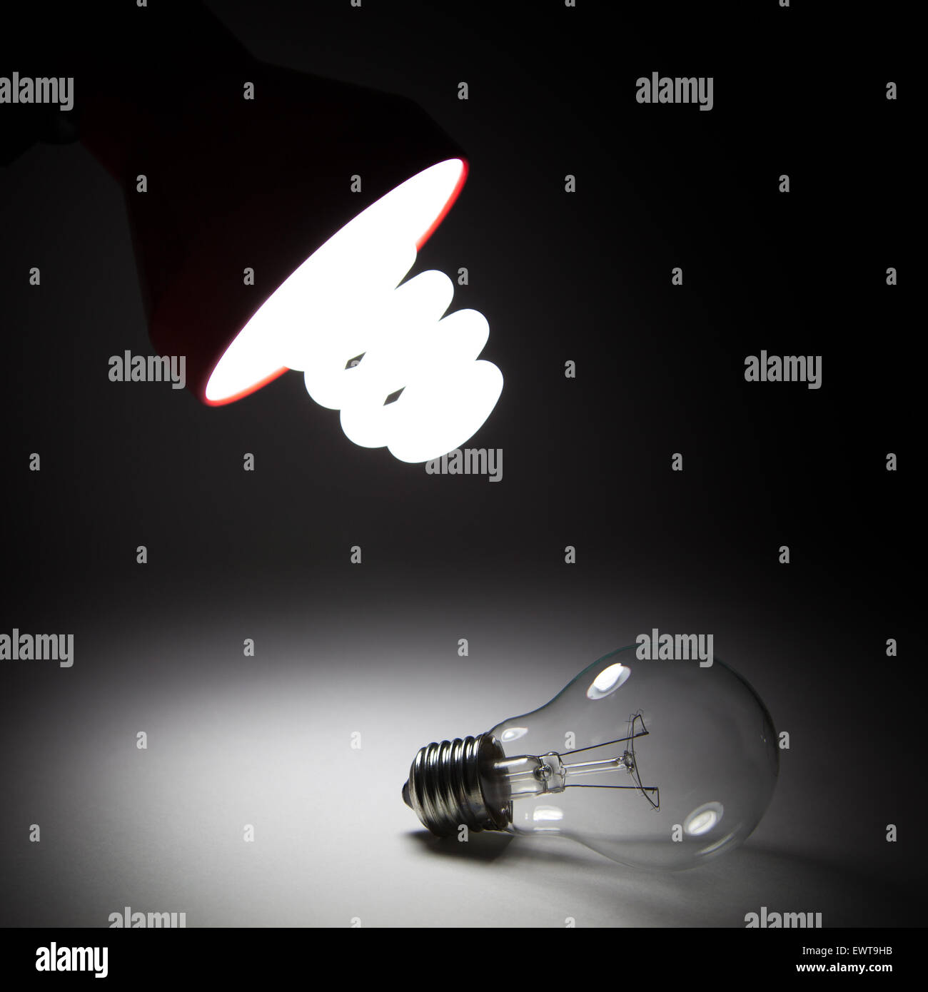 Power saving bulb is lighting from the top. An old one with incandescent changed is on the table. Stock Photo