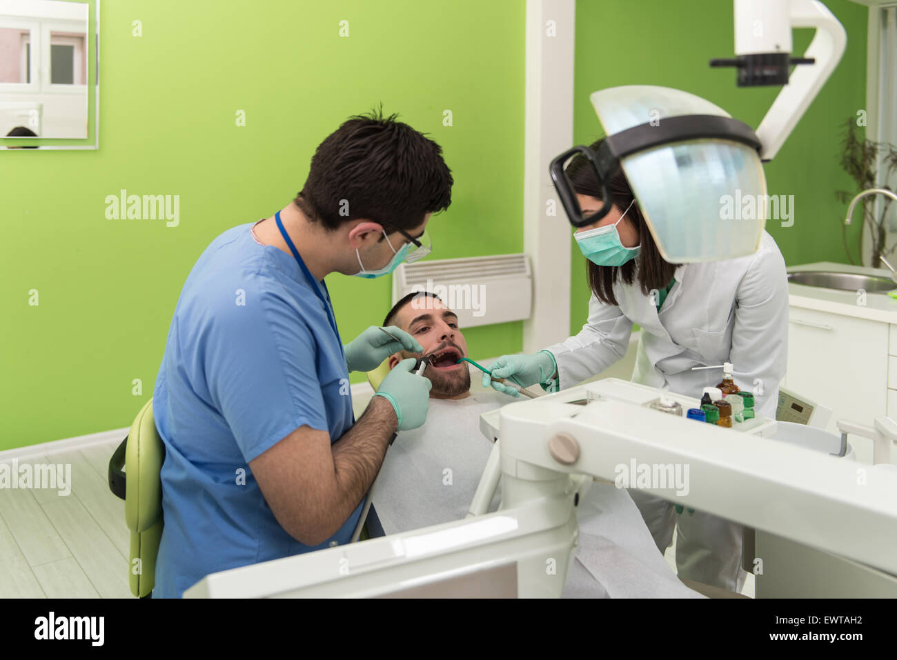 Male Patient With Dentist And Assistant In A Dental Treatment Wearing