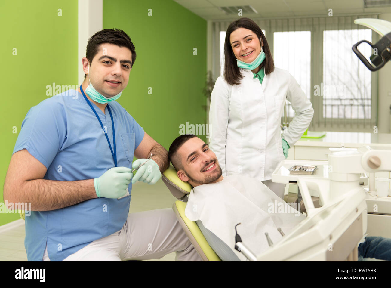 Male Patient With Dentist And Assistant In A Dental Treatment Wearing