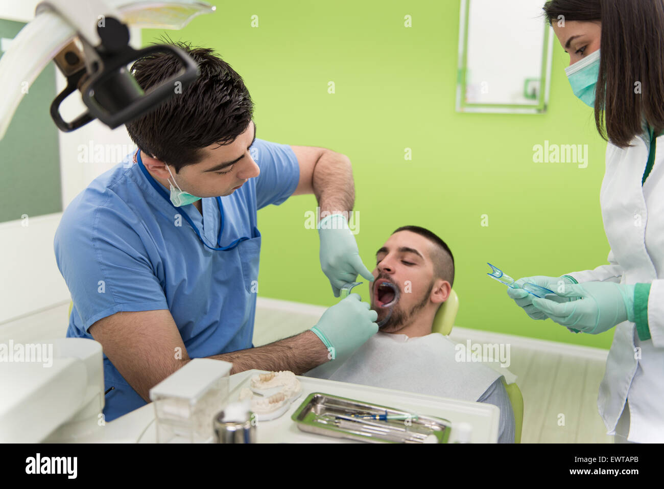 Male Patient With Dentist And Assistant In A Dental Treatment Wearing