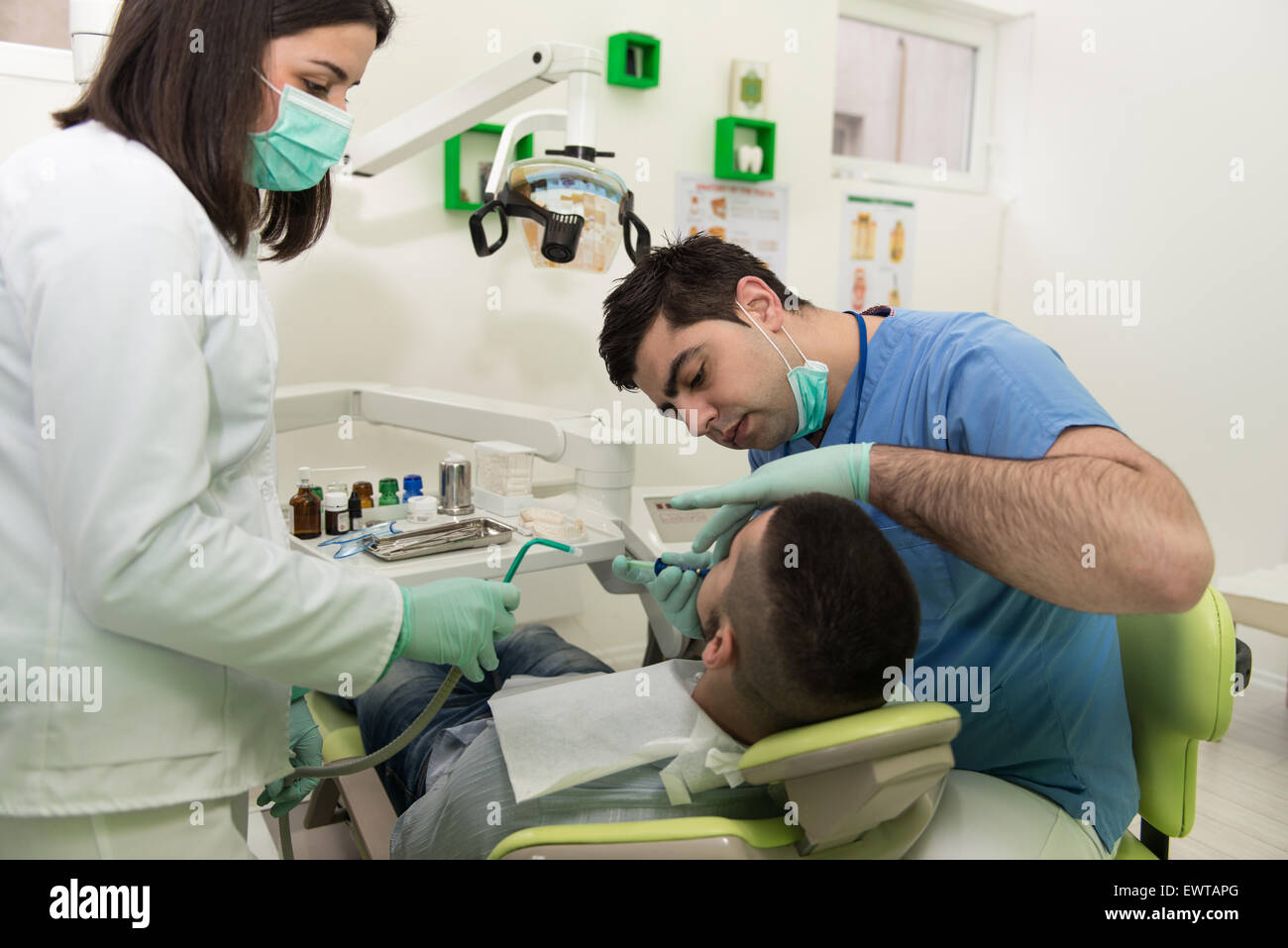 Male Patient With Dentist And Assistant In A Dental Treatment Wearing