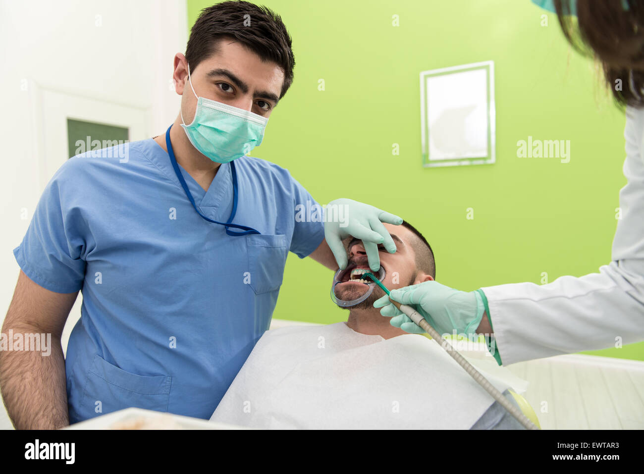 Male Patient With Dentist And Assistant In A Dental Treatment Wearing