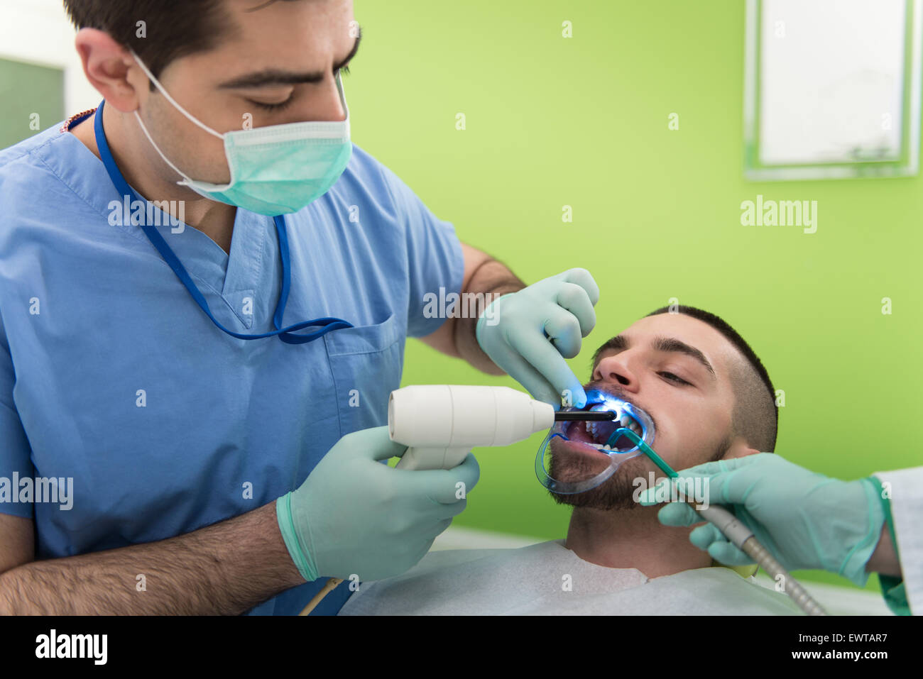 Male Patient With Dentist And Assistant In A Dental Treatment Wearing
