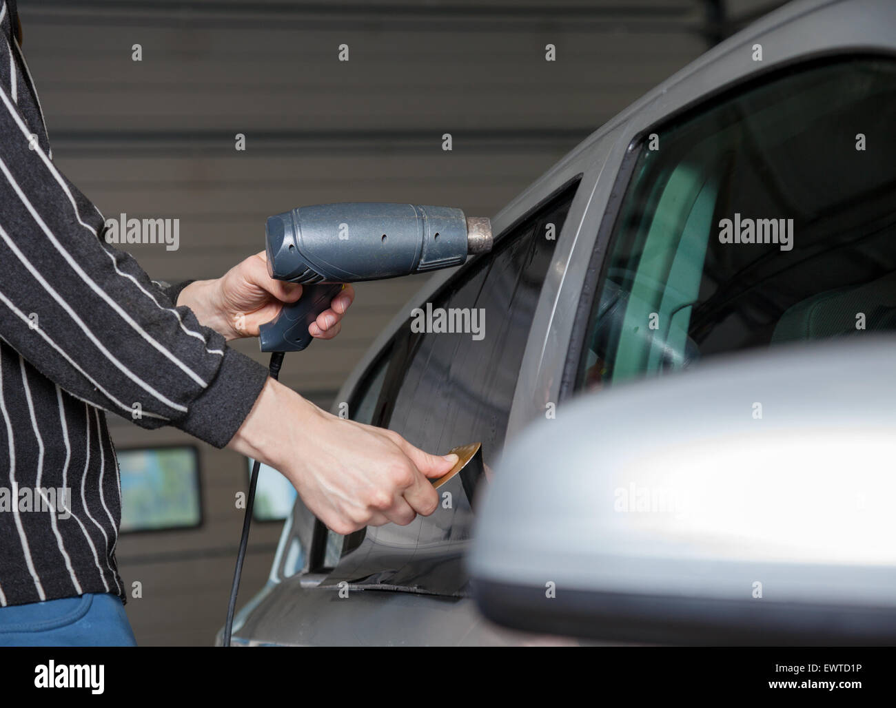 Applying tinting foil on a car window in a garage Stock Photo