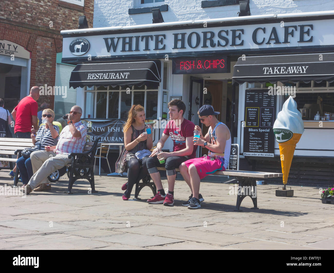 People relaxing with cool drinks outside the White Horse Café in Thirsk Market Place in the town centre on a hot summers day Stock Photo