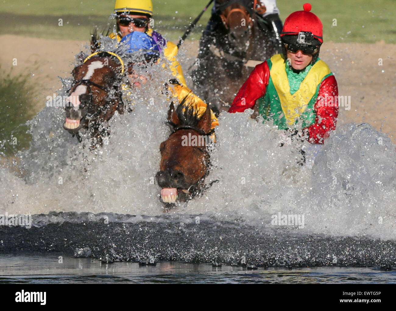 Hamburg, Germany. 30th June, 2015. Equastrians Cevin Chan on Kazzio (l-r), Julian Marinov on Samurai and Lukas Sloup on Laendler chase their horses through a pond during the Alpine Motorenoel-Seejagdrennen equestrian galloping race at the horse race track in Hamburg, Germany, 30 June 2015. Photo: Axel Heimken/dpa/Alamy Live News Stock Photo