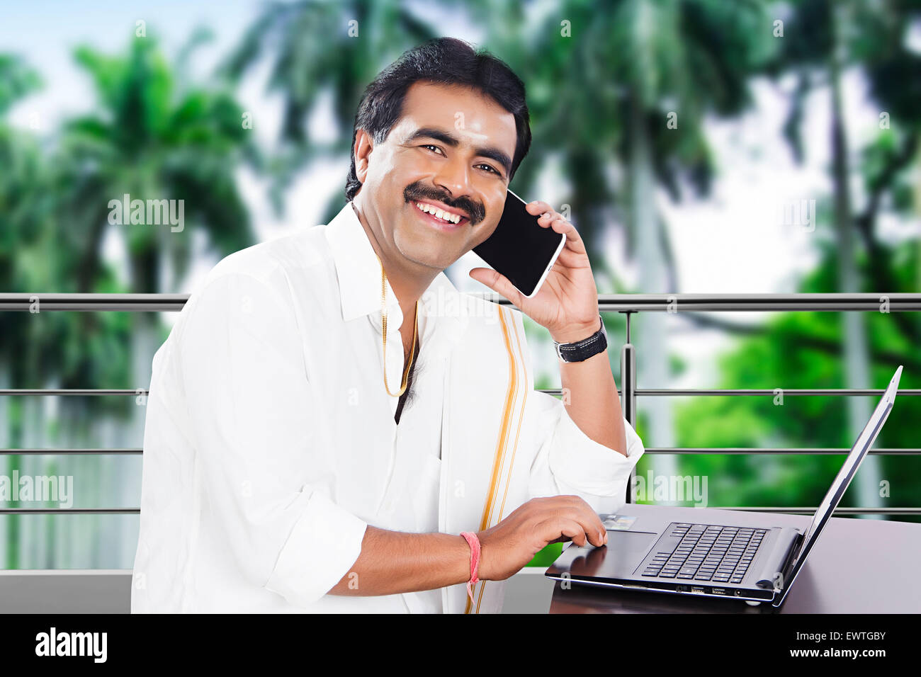 1 South Indian man laptop working and talking Cell phone Stock Photo