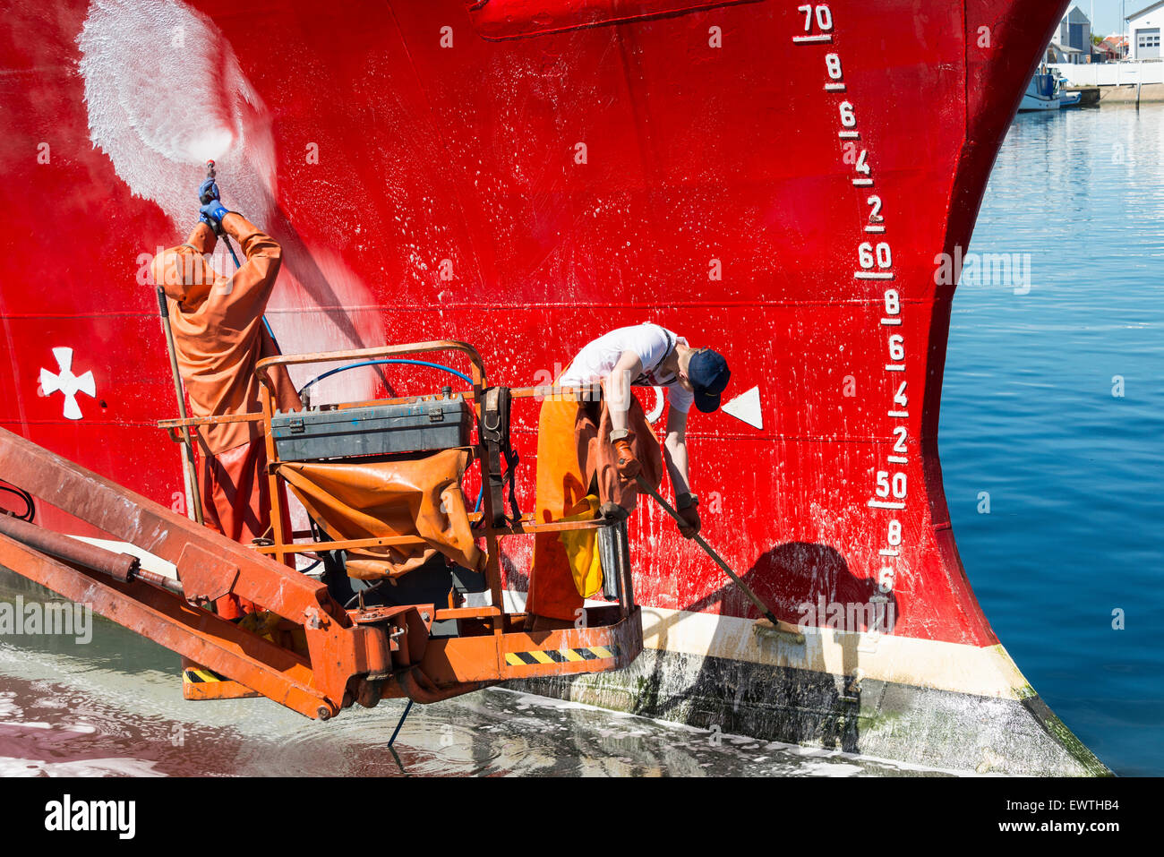 Workmen cleaning hull of fishing boat, Skagen Harbour, Skagen, North Jutland Region, Denmark Stock Photo