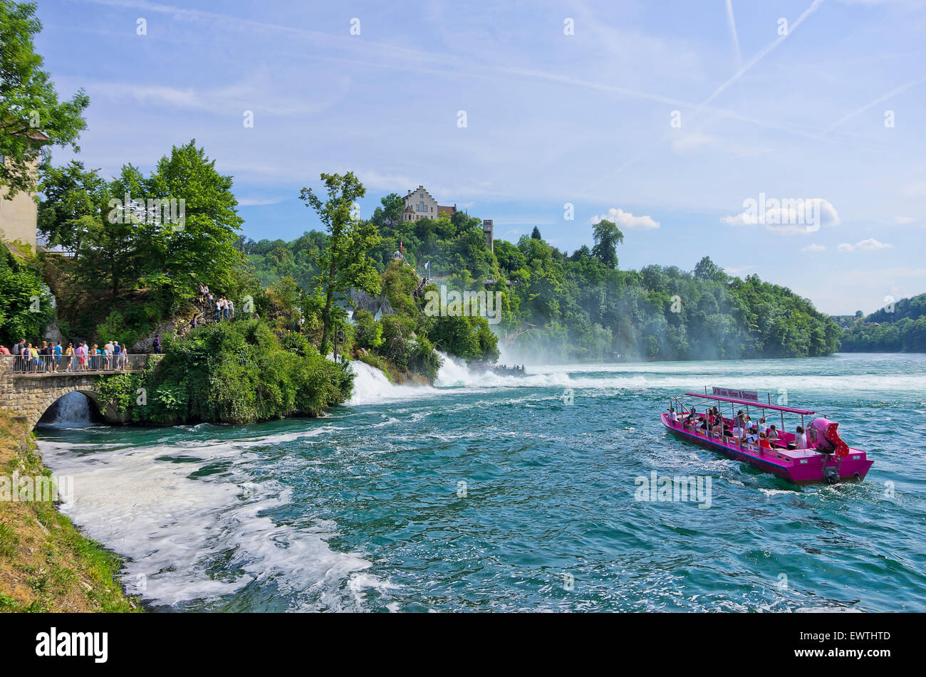 Tourists by land and by water gaze at the Rhine Falls in Schaffhausen, Switzerland. Stock Photo
