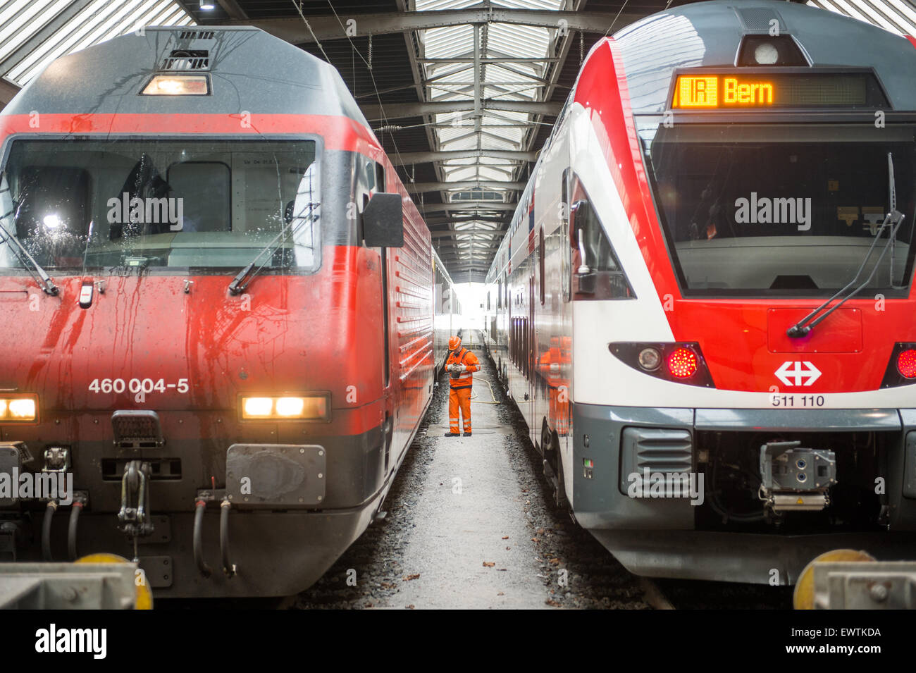 Workman wearing orange standing between trains at the train station in Zurich Switzerland, Europe Stock Photo