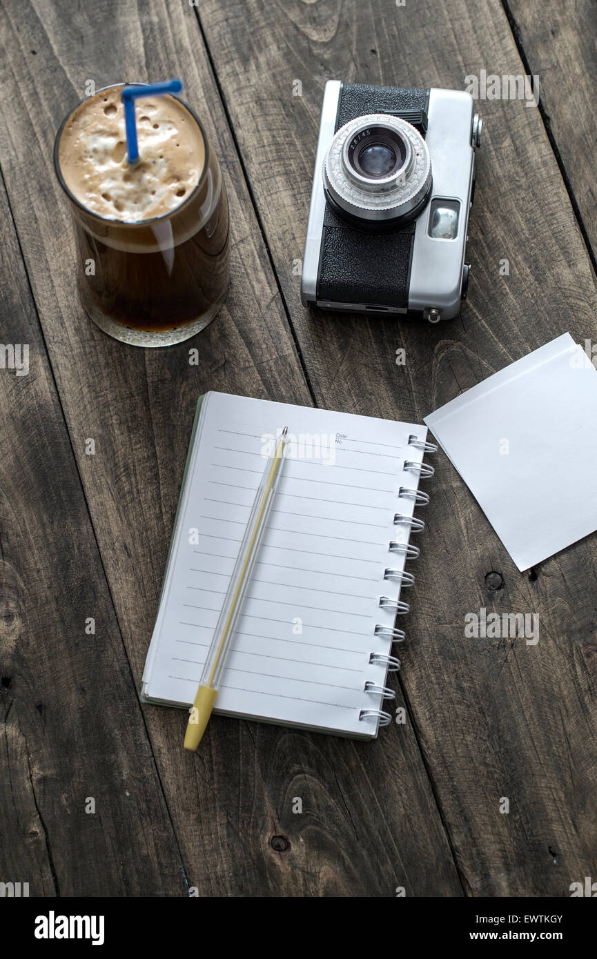 Analogue photo camera on a table with coffee and paper notes Stock Photo