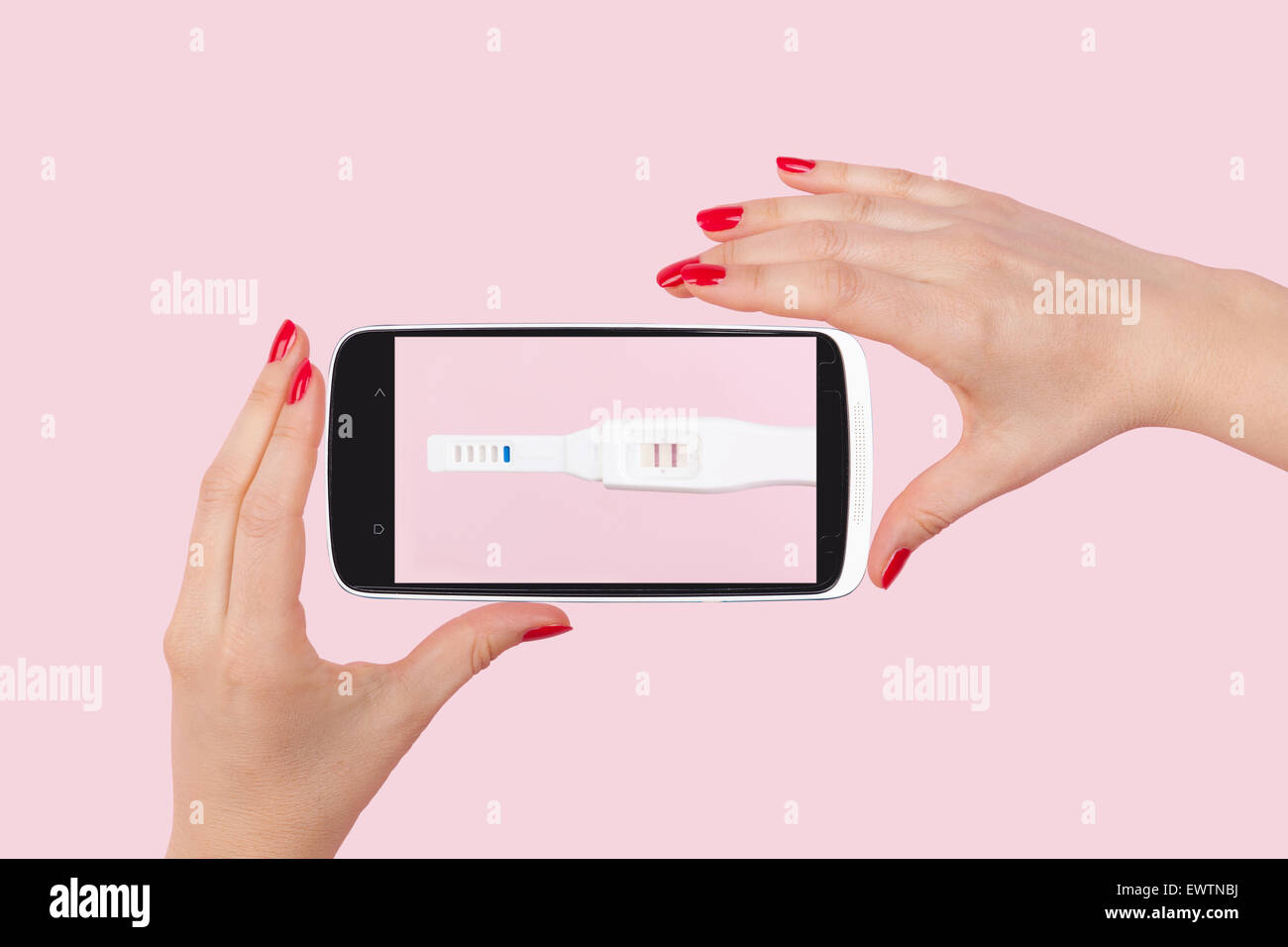 Beautiful female hand with red fingernails holding smartphone with positive pregnancy test isolated on pink background. Stock Photo