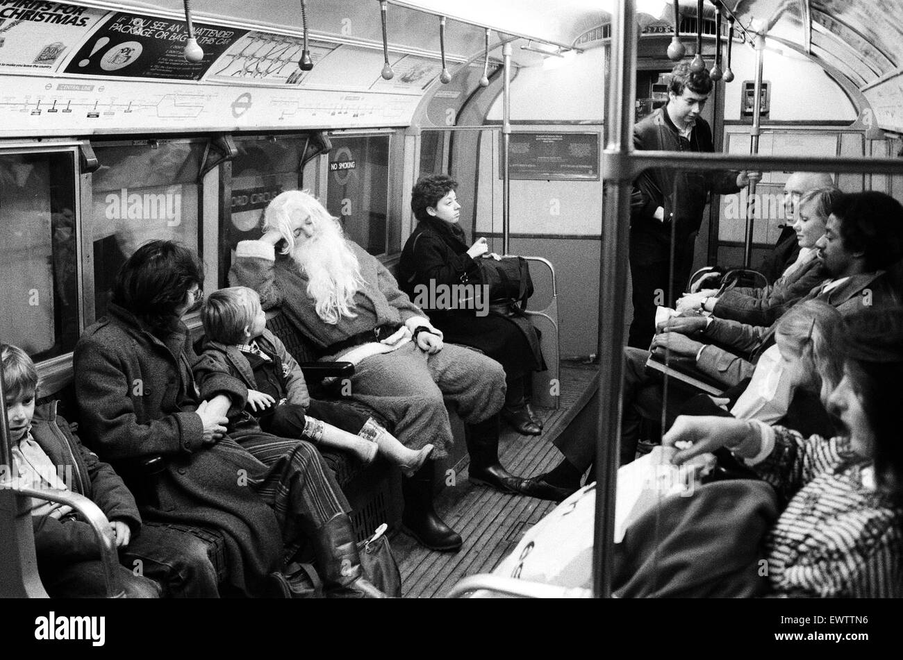 Father Christmas, of Bentall's Store, Ealing, takes the tube to pick up his sleigh. He seems to get no reaction from the commuters. 20th December 1984. Stock Photo