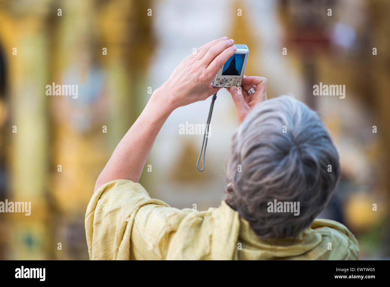 A tourist taking a close-up photograph of Shwedagon Pagoda in Yangon, Myanmar (Burma). Stock Photo