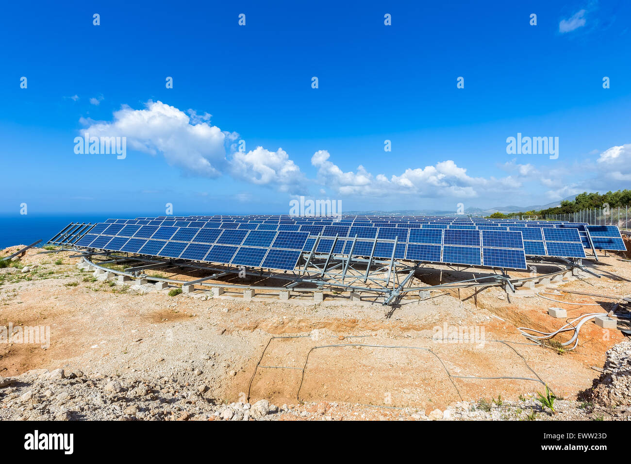 Field of many solar panels in rows on rotatable metal construction near blue sea in greece Stock Photo